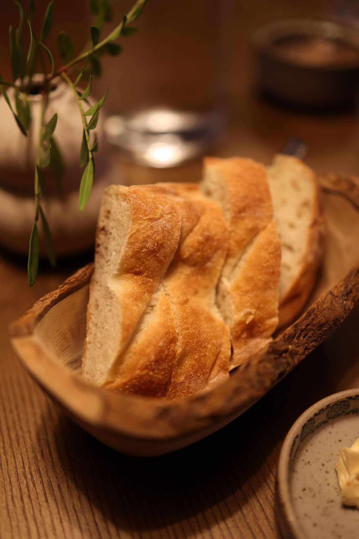 Cesta de pan de masa madre con mantequilla batida sobre mesa de madera