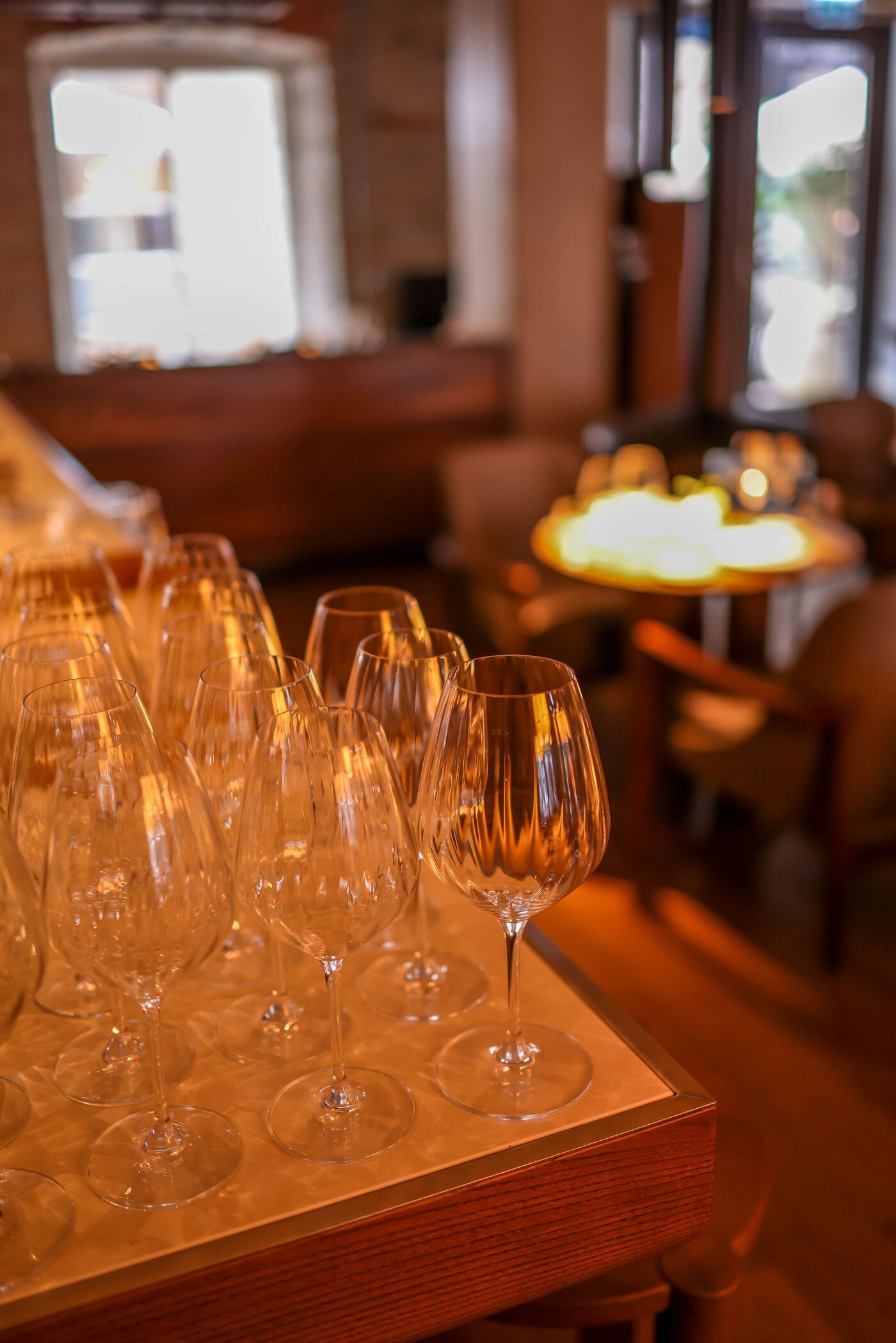 Copas de vino preparadas sobre el aparador, con la sala iluminada al fondo