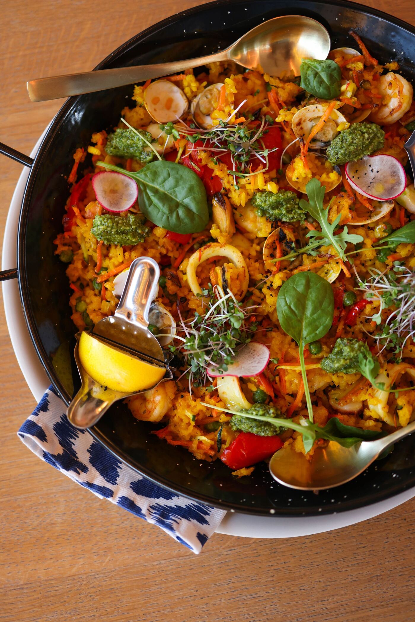 Arroz de marisco en paellera con calamar, almejas, limón y hierbas frescas